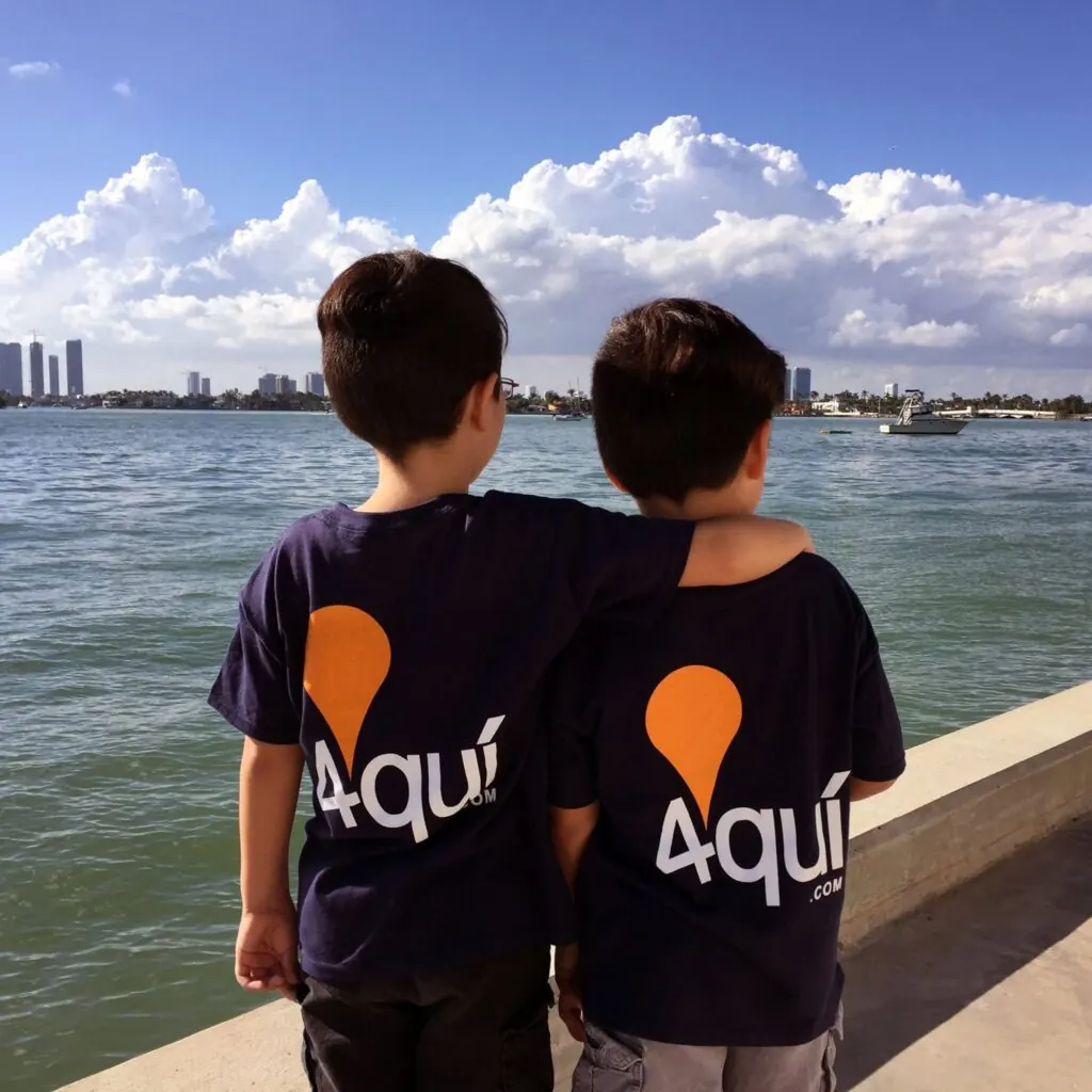 Dos jóvenes con camisetas de 4quí frente al mar