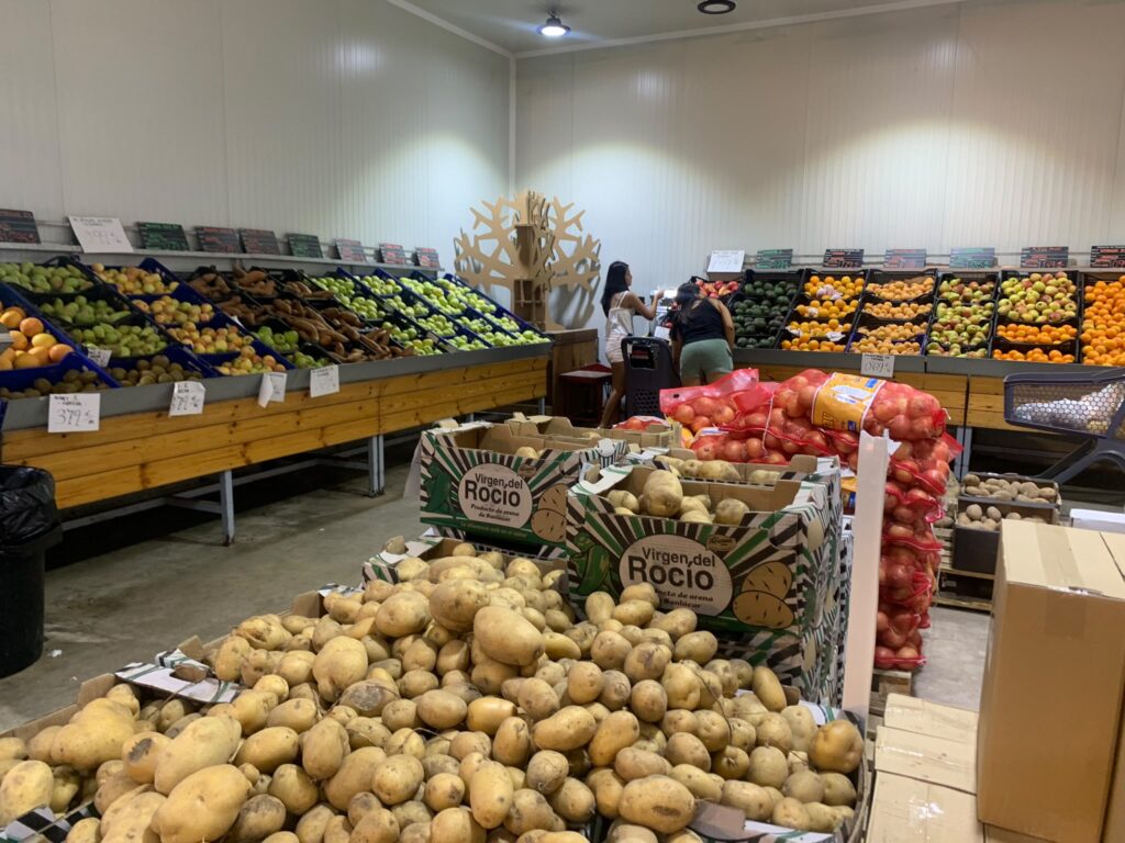 Frutería con producto fresco y personas comprando